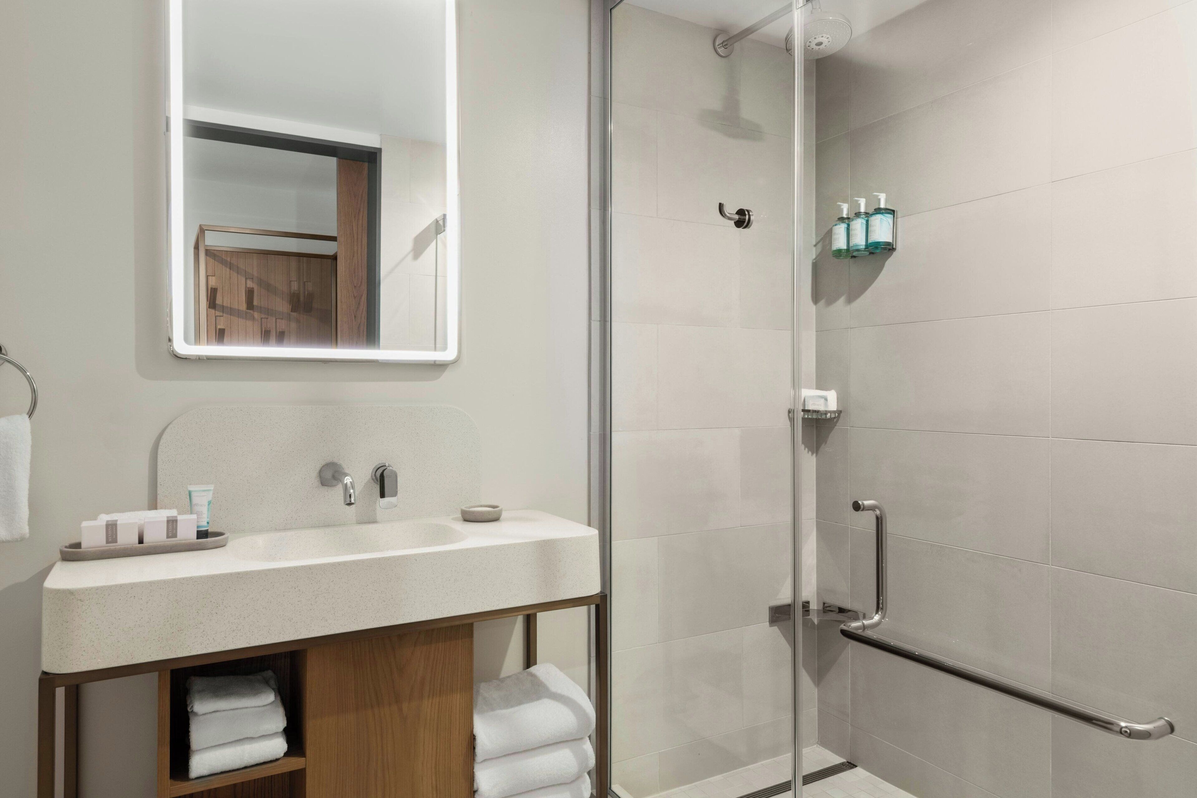 Une salle de bain moderne avec une douche à parois de verre, un meuble-lavabo et un miroir.