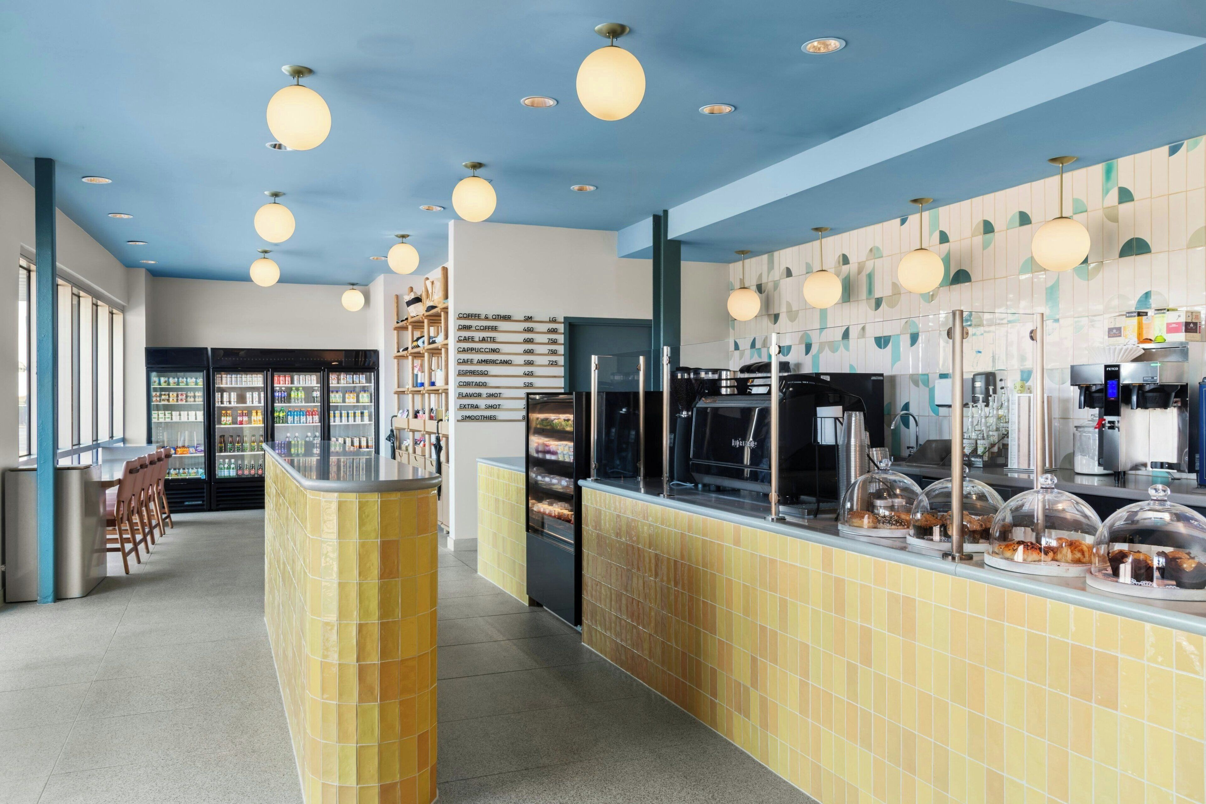 A cafe interior with a counter, beverage dispensers, and a menu board.