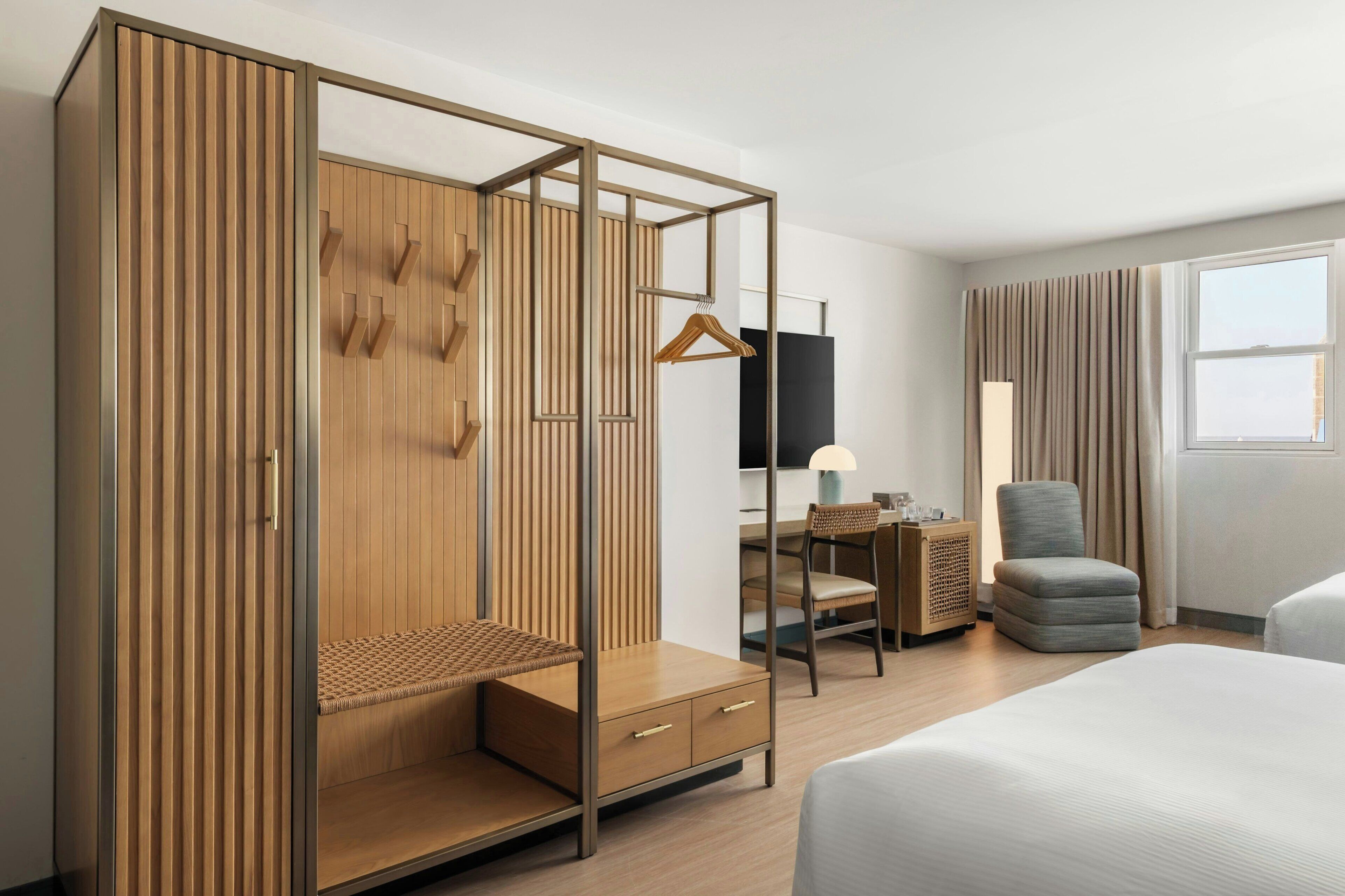 Una habitación de hotel moderna con un armario de madera, un escritorio con una silla, un sofá y una cama.