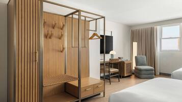Una habitación de hotel moderna con un armario de madera, un escritorio con una silla, un sofá y una cama.