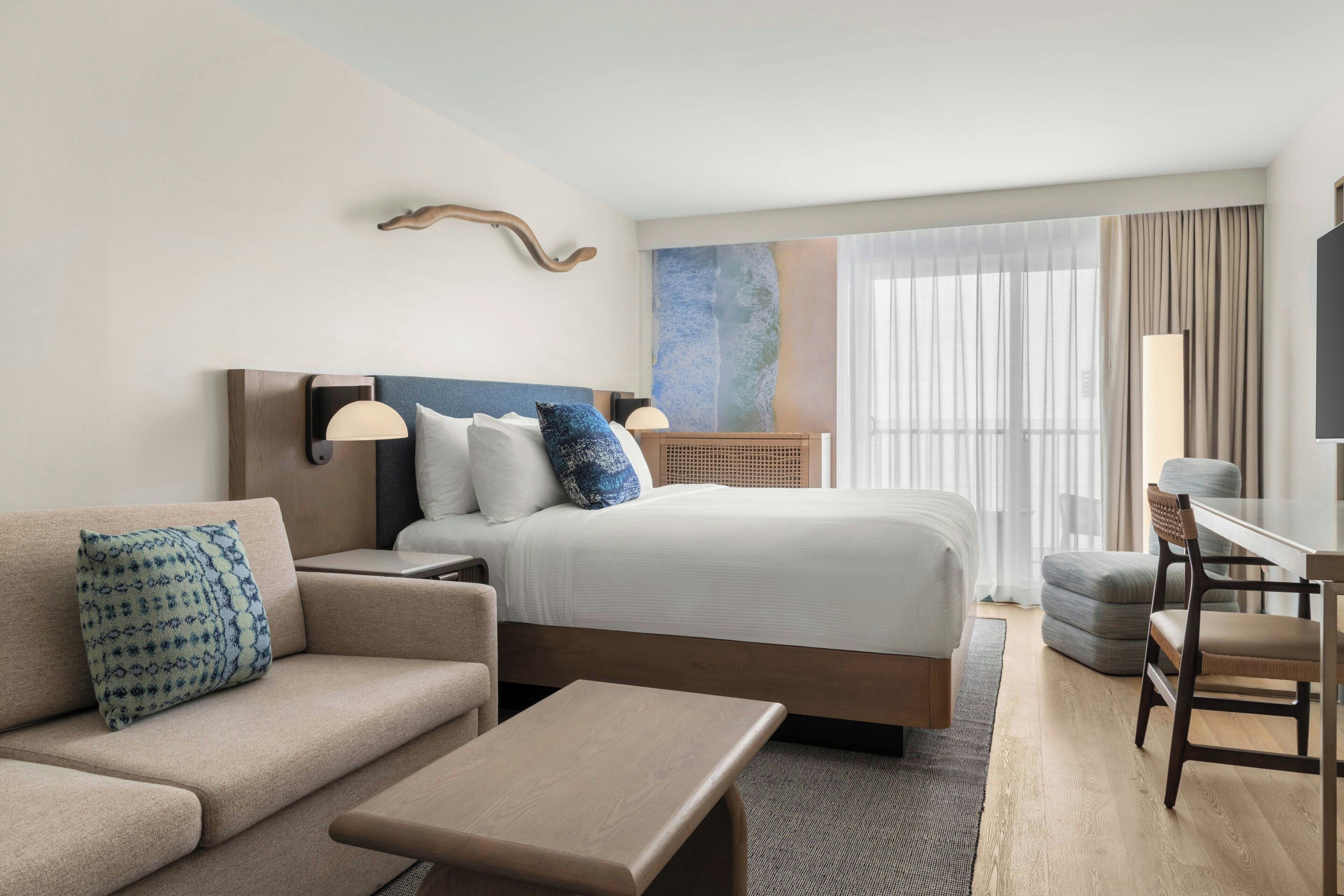 Una habitación de hotel moderna con una cama, un sofá, un escritorio y una silla.