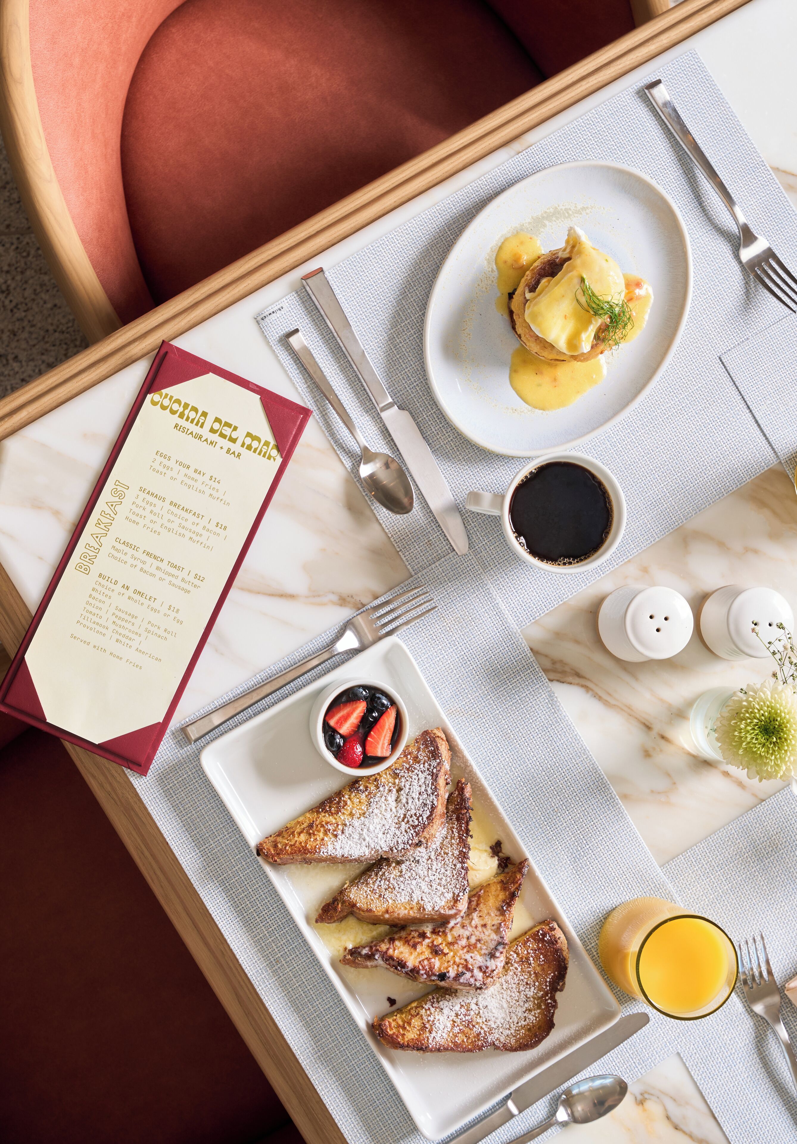 A breakfast tray with eggs benedict, toast, strawberries, coffee, and orange juice.