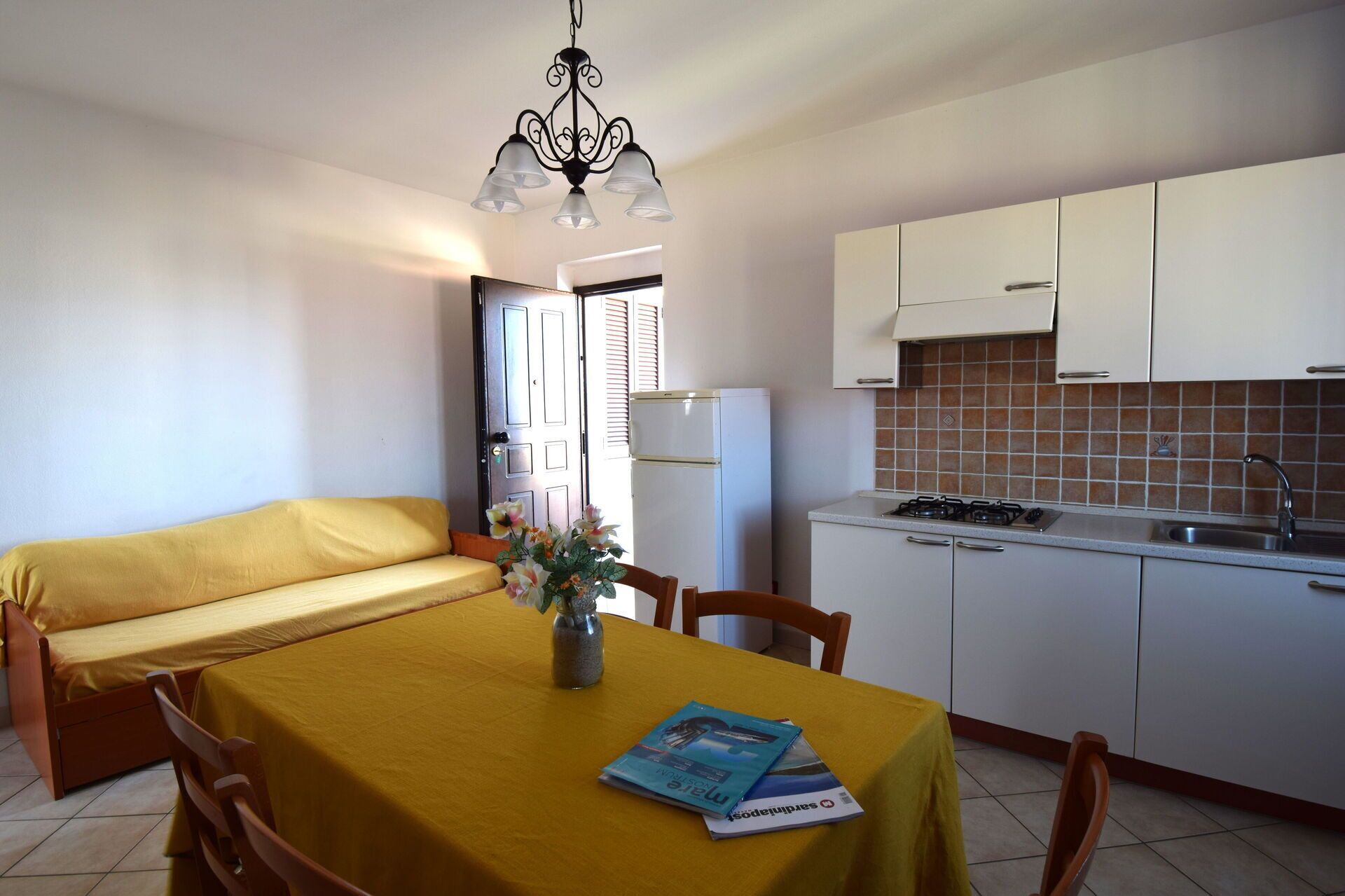 Un espace de vie compact comprenant une table à manger, un canapé et une kitchenette.