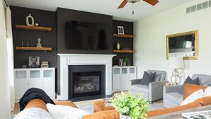 A living room with a fireplace, sofas, a coffee table, and a television. - Abe's Hideaway - Arcade, Hot Tub, Home Theater - Quiet upscale neighborhood (Springfield)