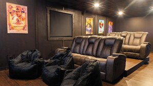 A home theater room with leather recliners, a large screen, and movie posters on the wall. - Abe's Hideaway - Arcade, Hot Tub, Home Theater - Quiet upscale neighborhood (Springfield)
