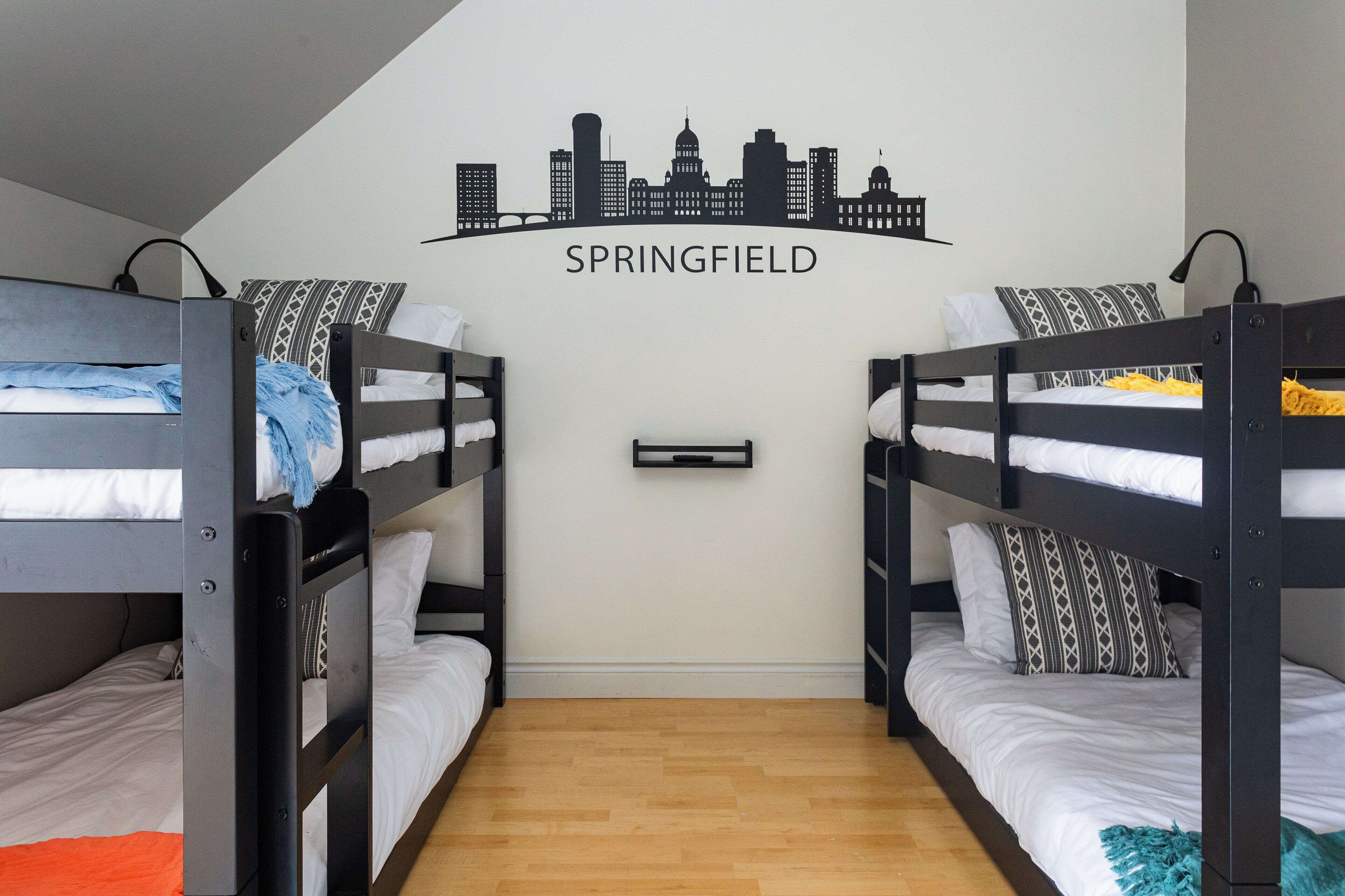 Ein Zimmer mit zwei Etagenbetten, einer Wandmalerei mit Stadtansicht und einem Holzboden.