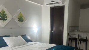 A hotel room with a bed, a desk, two chairs, an air conditioning unit, and wall art. - Rent your retreat in Ponta Negra: comfort and beauty in the best location! (Ponta Negra Natal)