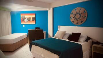Un dormitorio con una cama, un escritorio, una silla y una pared con un cuadro y un adorno decorativo.