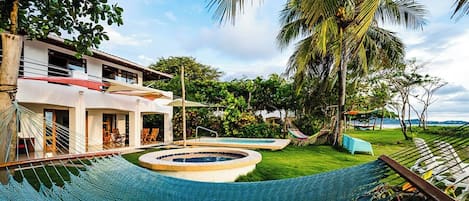 A pool area with a hammock, palm trees, and a view of the ocean.