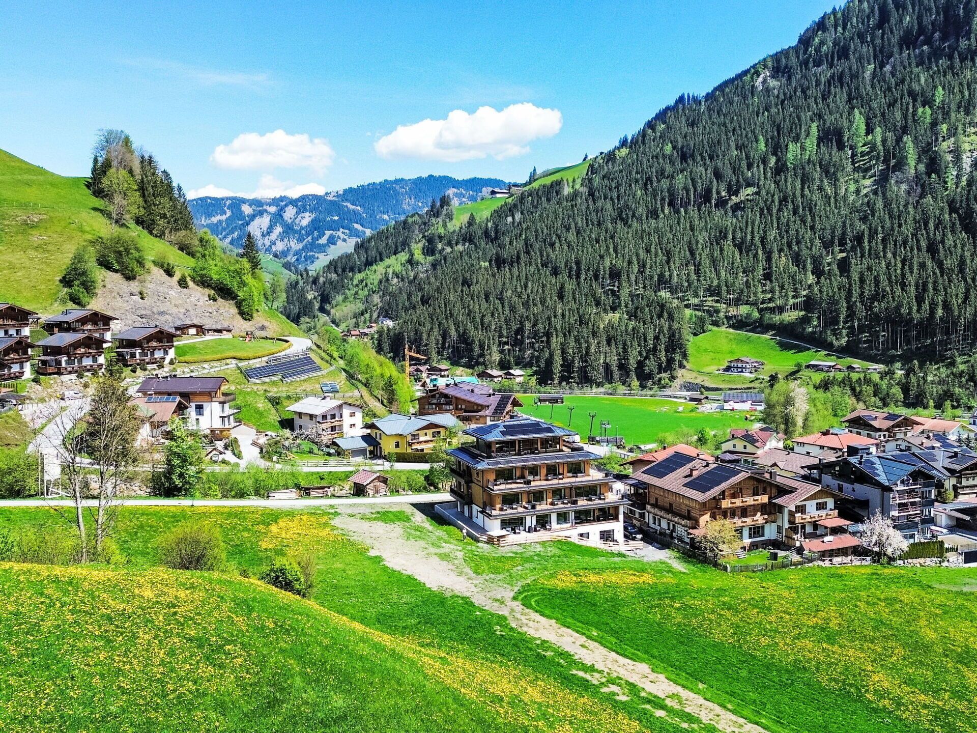 Un village de montagne avec des maisons traditionnelles en bois, une piste de ski et une vallée verdoyante.