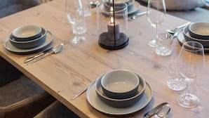 Una mesa de comedor dispuesta con platos, fuentes, cubiertos y vasos, con un candelabro como centro de mesa.
