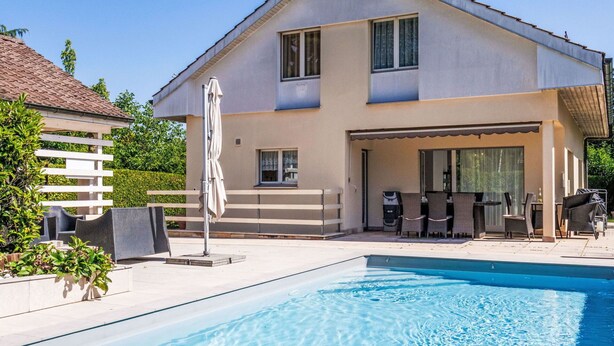 A two-story house with a swimming pool in the foreground.