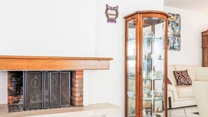 A living room with a fireplace, a glass display cabinet, and a sofa.
