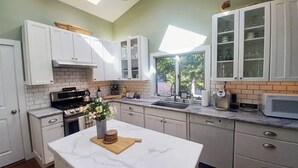A modern kitchen with white cabinets, a marble countertop, and a skylight.