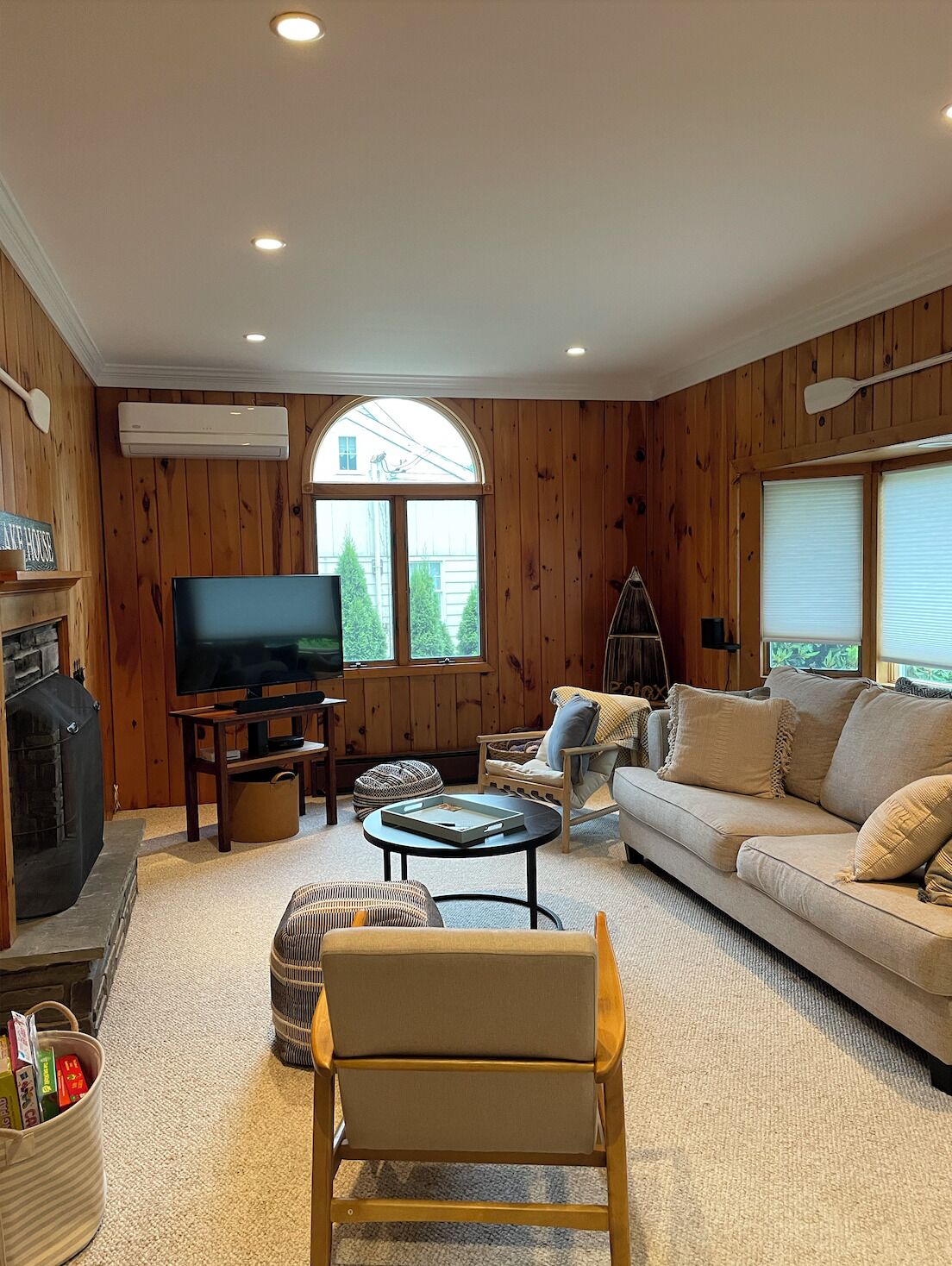Un salón acogedor con paredes de madera, una chimenea, un televisor, un sofá y una mesa de centro.