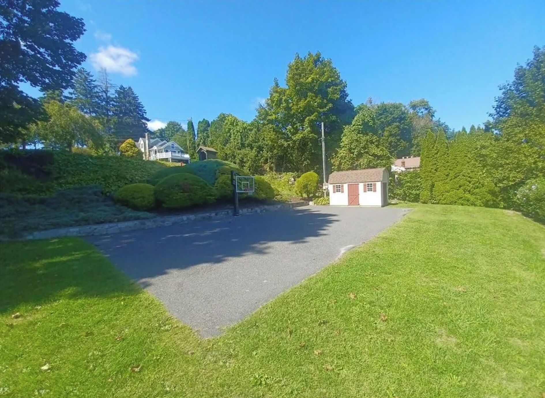 Una zona residencial con un camino de entrada pavimentado que lleva a una casa pequeña con una puerta roja.