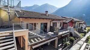Un edificio residencial de varios pisos con balcón, escaleras y vistas a montañas.