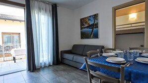 Un comedor con una mesa dispuesta para cuatro personas, un sofá y un cuadro en la pared.