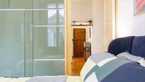 Un dormitorio con cama, armario y puerta que da a otra habitación.