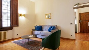 Una sala de estar con un sofá, un sillón verde, una mesa de centro y un tapete estampado.