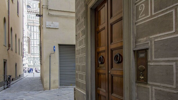 Una estrecha calle adoquinada con una persiana metálica cerrada y una puerta doble de madera con un aldabón de latón.
