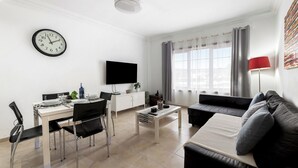 A modern living room with a dining area, a flat-screen TV, and a sofa with cushions. - Home2Book La Casita del Puerto, Playa Blanca (Playa Blanca)