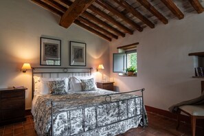 Une chambre à coucher avec un lit, deux lampes fixées au mur, une fenêtre donnant sur un beau paysage et un plafond en bois.