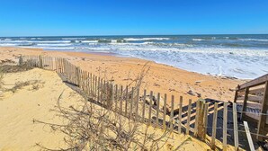 A beach with a wooden fence and a wooden walkway leading to a structure. -  Spacious Ormond Oceanfront  3 bedroom Condo (Ormond Beach)