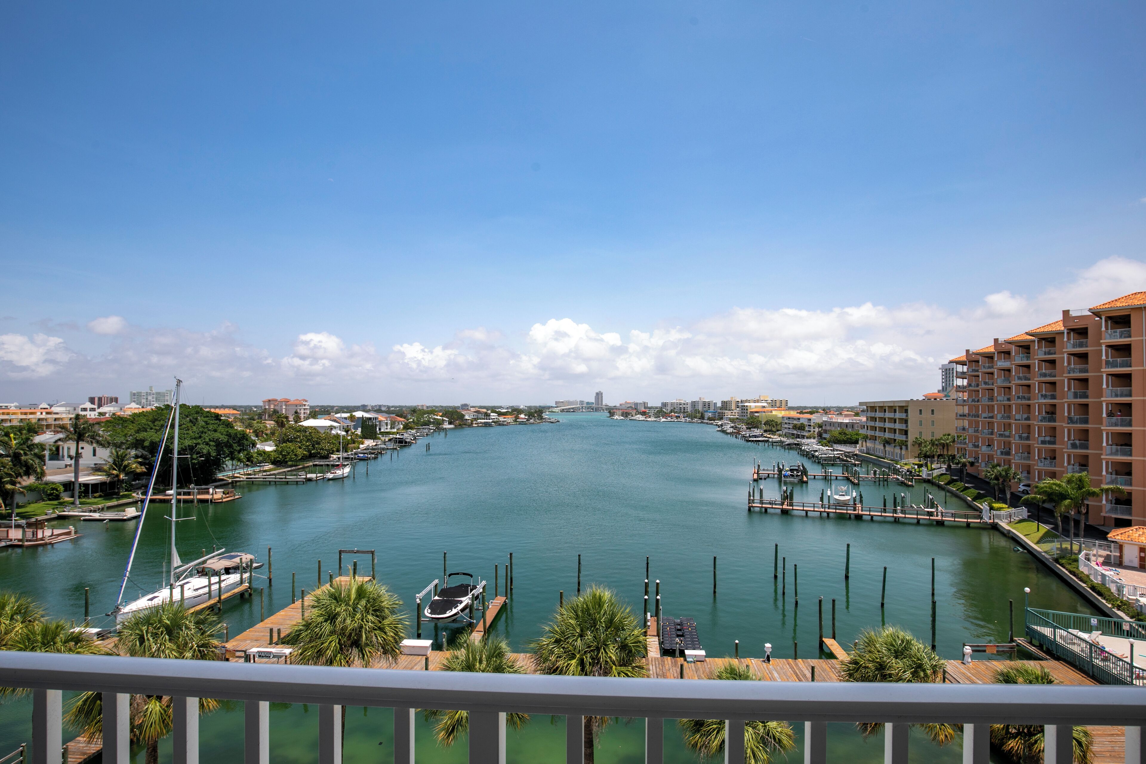 A marina with boats docked, surrounded by buildings and greenery.