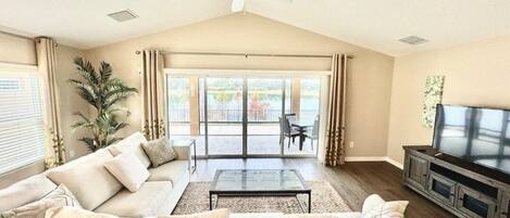 A living room with a sofa, coffee table, TV, and a ceiling fan.