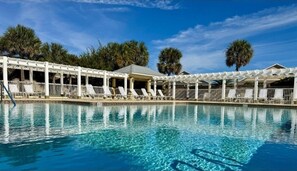 A swimming pool with white lounge chairs and a covered seating area. - The Villages with a View (The Villages)