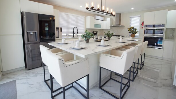 A modern kitchen with a central island, white cabinetry, stainless steel appliances, and a chandelier. - Luxury 6BR Villa w/ Pool, Rooftop Deck & lower level Lounge/ 2 Car garage/AC (Oistins)