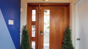 A wooden door with a glass panel, two potted plants, a doormat, and a ceiling light fixture. - Luxury 6BR Villa w/ Pool, Rooftop Deck & lower level Lounge/ 2 Car garage/AC (Oistins)