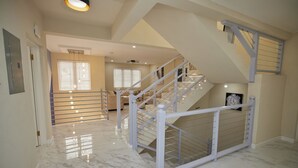 A spacious interior with a marble floor, a staircase with a white railing, and a ceiling fan. - Luxury 6BR Villa w/ Pool, Rooftop Deck & lower level Lounge/ 2 Car garage/AC (Oistins)