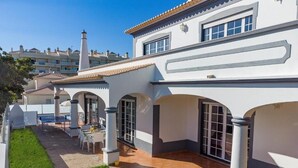 Un edificio blanco con techo de tejas y varios arcos. Cuenta con un patio amueblado con mesa y sillas.
