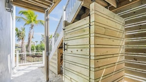 A wooden structure with a metal gate, a staircase, and a view of palm trees. - Shell Shack - New Luxurious Home (Sanibel)