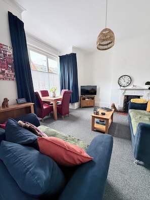 A living room with a sofa, a television, a fireplace, and a dining area. - Alfie’s Den, Bridlington (East Riding of Yorkshire)