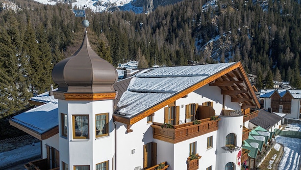 Un immeuble à plusieurs étages doté de balcons en bois, une tour centrale surmontée d’un dôme et un toit recouvert de neige.