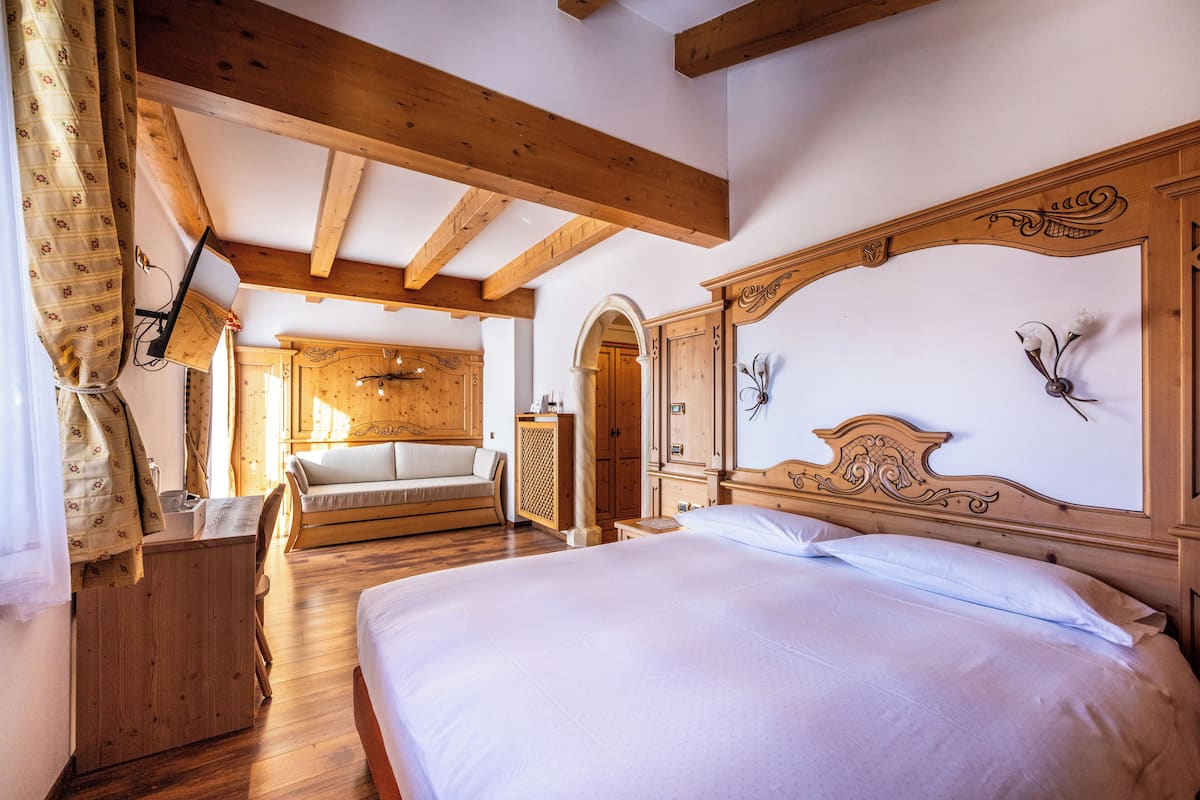 A room with a large bed, a wooden desk, and a wooden wardrobe.