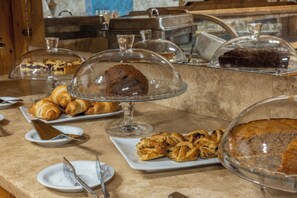 Un bufé con diversos pasteles y postres bajo campanas de vidrio.