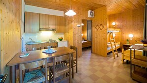 A cozy wooden cabin with a kitchen, dining area, and a sleeping area with a ladder. - Villaggio California Bungalow for 5 persons (Eraclea)