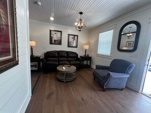 A living room with a leather sofa, a round coffee table, a blue armchair, and a chandelier.