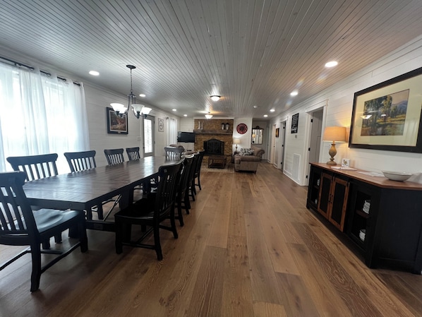 A spacious dining area with a long wooden table and chairs, a fireplace, and a television.