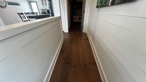 Un pasillo estrecho con suelo de madera y paredes blancas.