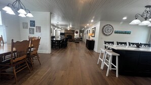 Una cocina amplia con suelo de madera, paredes blancas e iluminación moderna.