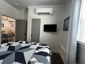 Quarto com uma cama, ar condicionado, televisão e uma porta.