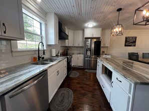 A modern kitchen with white cabinets, stainless steel appliances, and a marble countertop.