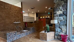 A spacious lobby with a tiled floor, a stone wall, and a reception area.