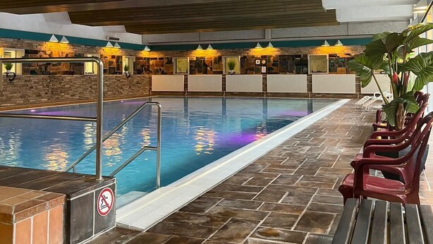 A swimming pool with a no diving sign, surrounded by lounge chairs and a brick wall.