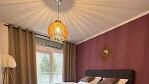 A bedroom with a large bed, a floor lamp, and a ceiling light fixture.
